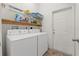 Functional laundry room with washer, dryer, shelving, and a convenient exterior door at 7059 Wirevine Dr, Brooksville, FL 34602