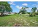 Large backyard with well-maintained green grass, trees and patio seating at 7133 Box Elder Dr, Port Richey, FL 34668