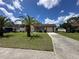 Single-story home featuring an attached garage, long driveway, and mature palm trees at 8312 Split Rail Ln, Hudson, FL 34667