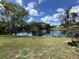 Picturesque view of a serene lake reflecting the blue sky, surrounded by trees and manicured lawn at 8312 Split Rail Ln, Hudson, FL 34667