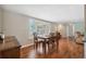 Bright dining room featuring hardwood floors, a classic wood table, and serene view through shuttered windows at 8404 Fishhawk Ave, New Port Richey, FL 34653