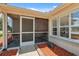 Close-up of a cozy screened porch with brick flooring, shuttered windows, and outdoor seating at 8404 Fishhawk Ave, New Port Richey, FL 34653