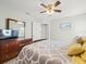 Comfortable bedroom with a wooden dresser, bed with patterned bedding and a ceiling fan at 8457 Southern Charm Cir, Brooksville, FL 34613