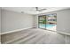 Bedroom with hardwood flooring and sliding glass doors providing access to a screened-in lanai and pool at 9921 San Mateo Way, Port Richey, FL 34668