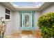 Charming front door with sidelights is accented by a welcome mat and bright green shrubbery at 9921 San Mateo Way, Port Richey, FL 34668