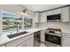 Well-lit kitchen featuring stainless steel appliances, stone countertops and a window with a view of the pool at 9921 San Mateo Way, Port Richey, FL 34668