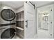 Functional laundry area with modern machines, shelving, and a barn door leading to the bathroom at 9921 San Mateo Way, Port Richey, FL 34668