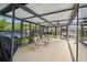 Enclosed patio with comfortable seating overlooks the sparkling pool and lush landscaping at 9921 San Mateo Way, Port Richey, FL 34668