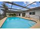Private in-ground pool with screened-in enclosure, patio seating, and lush landscaping at 9921 San Mateo Way, Port Richey, FL 34668