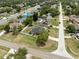 An aerial view shows the house with a long drive, in a neighborhood with other houses and many trees at 10091 Bannister St, Spring Hill, FL 34608