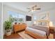 Well-lit bedroom with large window, TV, ceiling fan, and hardwood floors at 10091 Bannister St, Spring Hill, FL 34608