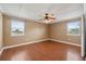 Bright bedroom with two windows offering plenty of natural light, ceiling fan, and hardwood floors at 10091 Bannister St, Spring Hill, FL 34608
