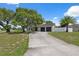 The house has a long driveway to a two-car garage and is surrounded by a white fence at 10091 Bannister St, Spring Hill, FL 34608