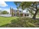 The home has a two-car garage, black shutters, chimney, palm tree, and is surrounded by a white fence at 10091 Bannister St, Spring Hill, FL 34608