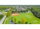 Aerial view of community baseball field, soccer goals, and pond amid lush greenery at 10115 Ringling St, New Port Richey, FL 34655
