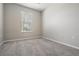A simple bedroom with neutral carpet, a window, and light-colored walls at 10115 Ringling St, New Port Richey, FL 34655
