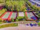 Aerial shot showcases tennis, volleyball, and basketball courts with parking, surrounded by lush greenery at 10115 Ringling St, New Port Richey, FL 34655