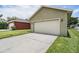 View of attached two car garage with long driveway and green grass at 10115 Ringling St, New Port Richey, FL 34655