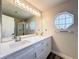 Bright bathroom with double sinks, large mirror with globe lighting, and an enclosed shower at 10124 Heathcliff St, Spring Hill, FL 34608