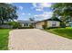 Charming home featuring a brick driveway, lush landscaping, and a well-maintained lawn at 1071 Lexington Ct, Largo, FL 33771