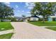 Charming home featuring a brick driveway, lush landscaping, and a well-maintained lawn at 1071 Lexington Ct, Largo, FL 33771