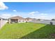Large backyard with a covered patio extending from the home, enclosed by a white fence at 1098 Old Windsor Way, Spring Hill, FL 34609