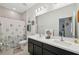 Well-lit bathroom featuring a double sink vanity, a large mirror, and a shower with a curtain at 1098 Old Windsor Way, Spring Hill, FL 34609