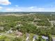 An aerial view shows homes nestled within a lush, green landscape of trees and blue skies on a sunny day at 11034 Flock Ave, Weeki Wachee, FL 34613