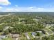 An aerial view shows homes nestled within a lush, green landscape of trees and blue skies on a sunny day at 11034 Flock Ave, Weeki Wachee, FL 34613