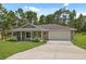 Well-maintained single-story home with a two-car garage, long driveway, and attractive landscaping at 11034 Flock Ave, Weeki Wachee, FL 34613