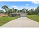Inviting single-story home boasting a long driveway leading to a two-car garage, complemented by a lush, green lawn at 11034 Flock Ave, Weeki Wachee, FL 34613