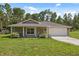 Charming single-story home with a well-manicured lawn, a covered front porch, and an attached two-car garage at 11034 Flock Ave, Weeki Wachee, FL 34613