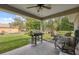 Covered patio with grill and outdoor furniture overlooking a spacious backyard and lush greenery at 11034 Flock Ave, Weeki Wachee, FL 34613