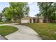 Charming home featuring a well-maintained lawn, mature trees, and a curved walkway leading to the front door at 1131 Bentley Ave, Spring Hill, FL 34608