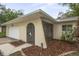 Close up on the house front, with a two car garage, an arched front door, and mature landscaping in the flower beds at 1131 Bentley Ave, Spring Hill, FL 34608