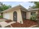 Inviting front entrance with an arched doorway, screened porch, and lush landscaping at 1131 Bentley Ave, Spring Hill, FL 34608