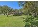 Lush backyard with mature trees and a well-maintained lawn, featuring a screened-in pool area at 12295 Clarendon Ct, Spring Hill, FL 34609