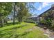Expansive backyard featuring a screened-in pool area, bordered by mature trees and manicured lawn at 12295 Clarendon Ct, Spring Hill, FL 34609