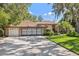 Charming home exterior with a manicured lawn, mature trees, and a spacious driveway at 12295 Clarendon Ct, Spring Hill, FL 34609
