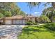 Charming home with a lush front yard, complemented by a brick driveway and a spacious three-car garage at 12295 Clarendon Ct, Spring Hill, FL 34609