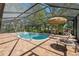Inviting screened-in pool and patio area with an umbrella and tile surround, perfect for outdoor relaxation at 12295 Clarendon Ct, Spring Hill, FL 34609