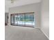 Bright living room with neutral carpet and sliding glass doors leading to a screened pool area at 13125 Jessica Dr, Spring Hill, FL 34609