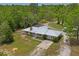 Aerial view of the house with lush greenery, an American flag, and a metal roof at 13345 Convent Garden Rd, Brooksville, FL 34613