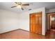 This bedroom features a fan, closet, wood-look flooring and access to the bathroom at 13345 Convent Garden Rd, Brooksville, FL 34613