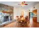 Dining room with stone fireplace, wood floors, ceiling fan and view into kitchen and patio at 13345 Convent Garden Rd, Brooksville, FL 34613