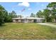 This charming ranch-style home offers a metal roof, stone accents, and a lovely front lawn with an American flag at 13345 Convent Garden Rd, Brooksville, FL 34613