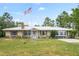 Ranch home showcasing stone accents, a metal roof, an American flag, and a well-manicured lawn at 13345 Convent Garden Rd, Brooksville, FL 34613
