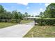 Ranch-style home is surrounded by a beautiful landscape, a metal gate, and a long, concrete driveway at 13345 Convent Garden Rd, Brooksville, FL 34613
