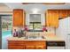 Cozy kitchen with wood cabinets, stainless steel sink, and a view of the pool at 13345 Convent Garden Rd, Brooksville, FL 34613