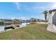 A large backyard with canal access, a wooden dock, a boat lift, and a patio at 13836 Darlene Ave, Hudson, FL 34667